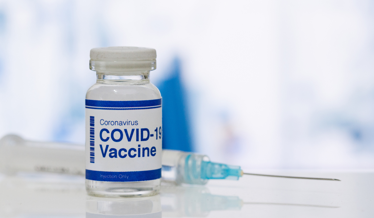 Na stole szczepionka Covid-19 i strzykawka z igłą.